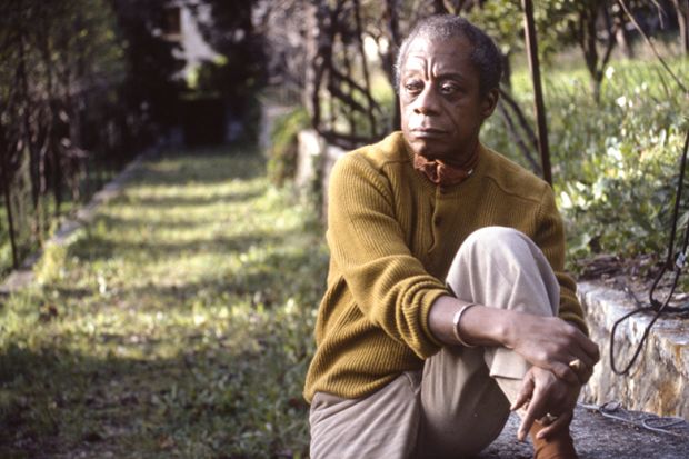 A man sits with his leg bent in front of him. In the background a grassy path leads into the distance